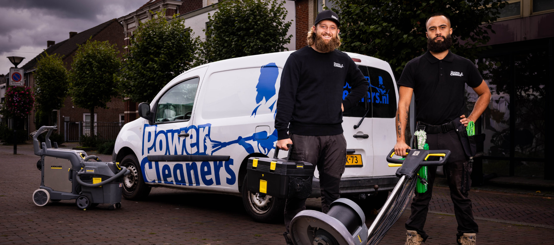Twee PowerCleaners-medewerkers met schoonmaakapparatuur voor de bedrijfsauto met PowerCleaners-logo
